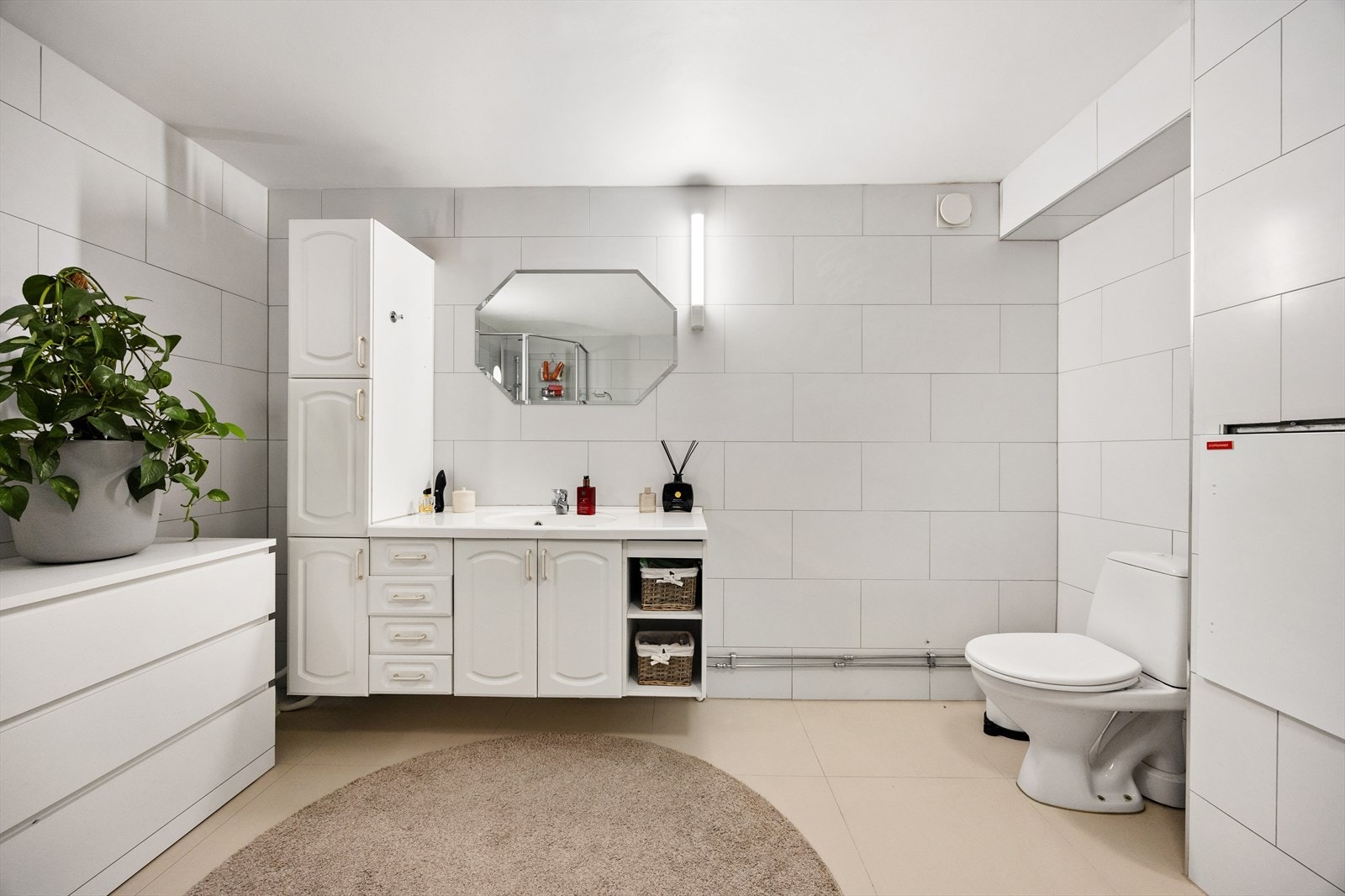 Badet er utstyrt med dusjkabinett, gulvstående wc og servantinnredning med skuffer, under- og sideskap Galleribilde