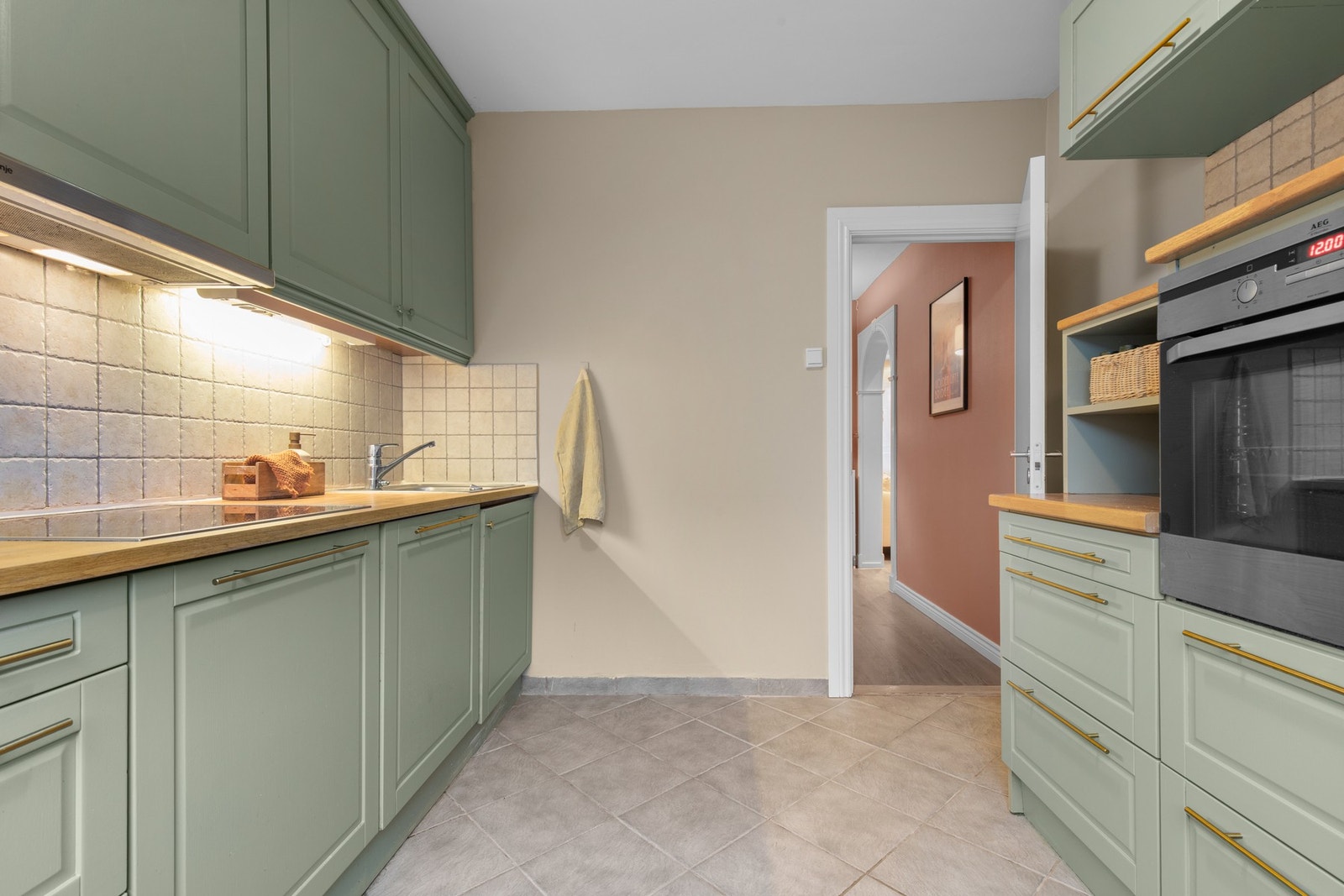 Kjøkken med profilerte fronter, fliser over benkeplate og ventilator tilkoblet ventilasjonsanlegget - et praktisk og ryddig rom for matlaging. Galleribilde