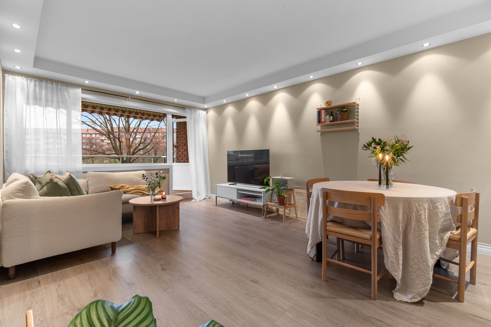 Lys og romslig stue med åpen løsning mot spiseplass, store vindusflater og direkte utgang til balkong som gir en luftig og innbydende atmosfære. Galleribilde