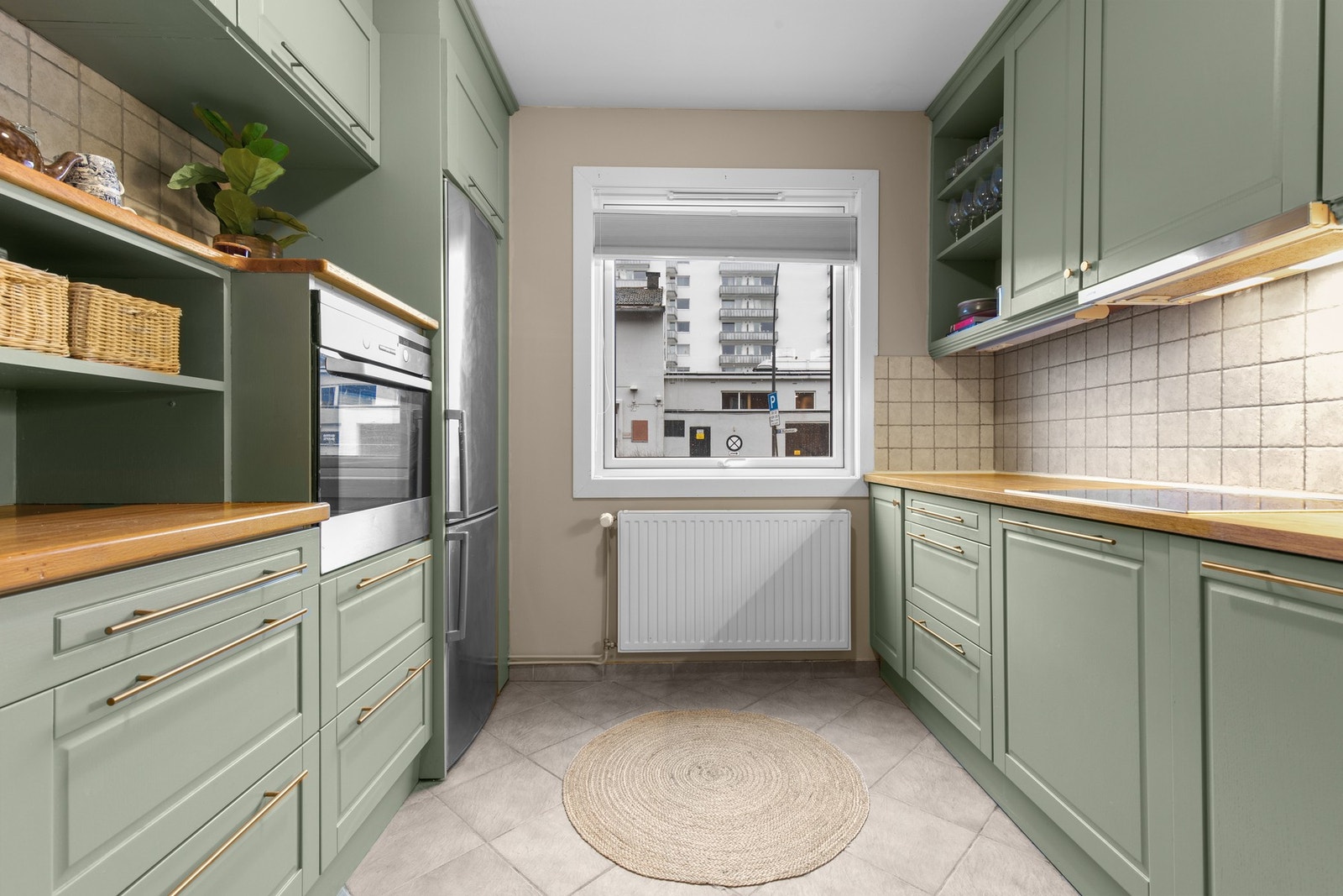 Funksjonelt kjøkken med praktisk gjennomgangsløsning, integrerte hvitevarer og smarte oppbevaringsløsninger i både over- og underskap. Galleribilde