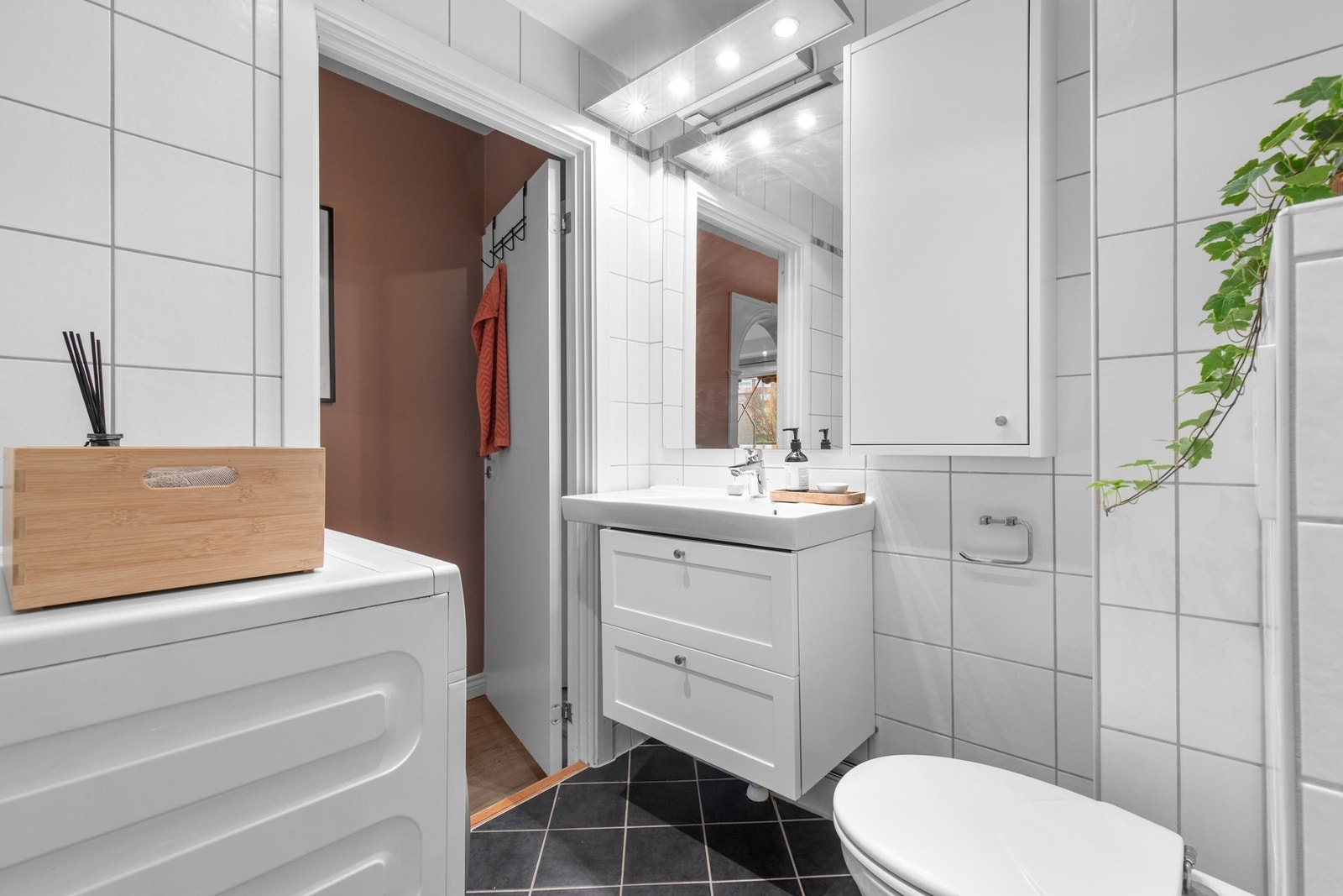 Stilrent baderom med fliser på gulv og vegg, mekanisk avtrekk styrt fra kjøkken og god planløsning som utnytter plassen effektivt. Galleribilde