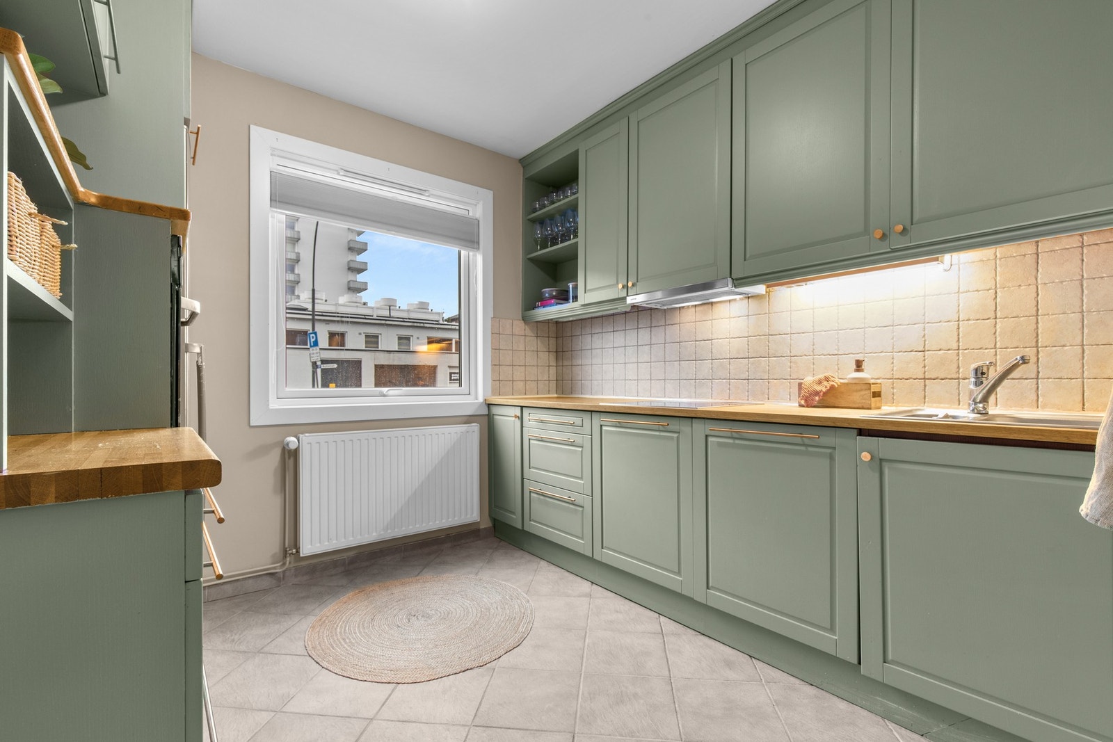 Tidløst kjøkken med rolige fargetoner, god benkeplass og naturlig lys fra vindu som gir et lyst og behagelig arbeidsmiljø. Galleribilde