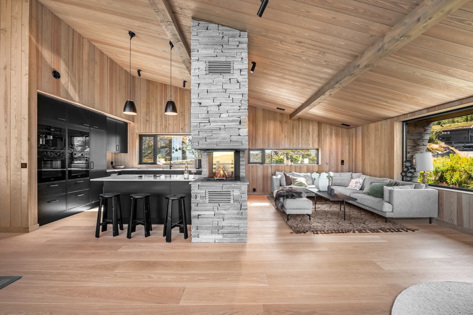 Storstuen er vidstrakt meg panoramautsikt, spisestue, delvis åpen kjøkkenløsning og sofagruppe i skjermet hjørne Galleribilde