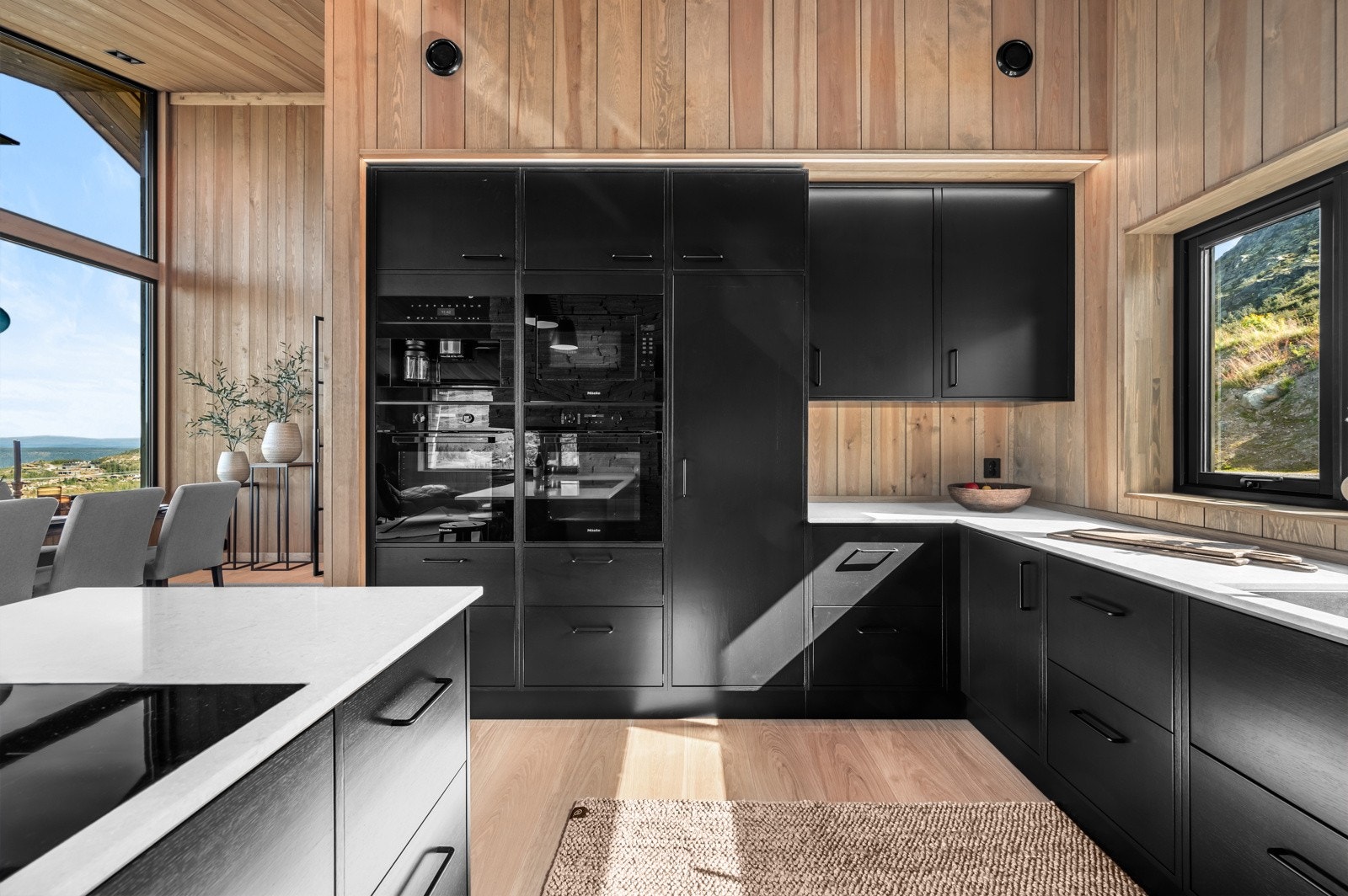 Lys benkeplate mot sorte fronter gir kjøkkenet et elegant og stilrent uttrykk Galleribilde