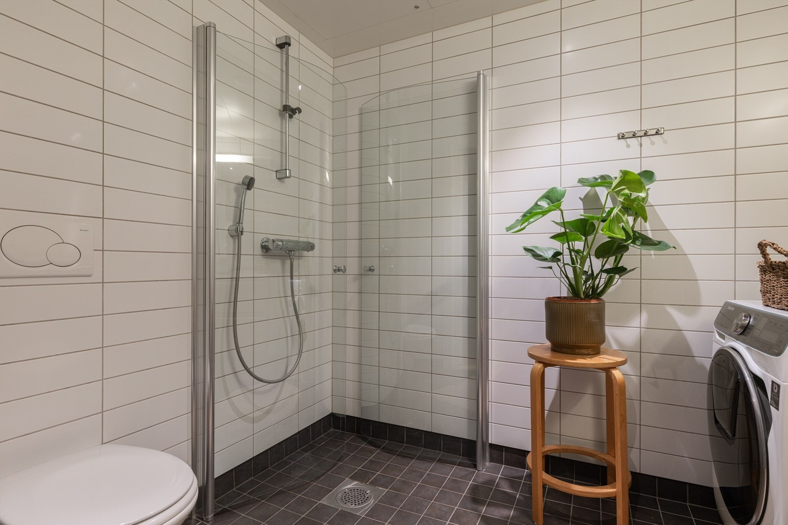 Rommet er innredet med servantskap med bolleservant, innmurt speil med belysning, vegghengt toalett med innebygget sisterne samt dusjnisje med innfellbare dusjvegger i herdet glass. Galleribilde