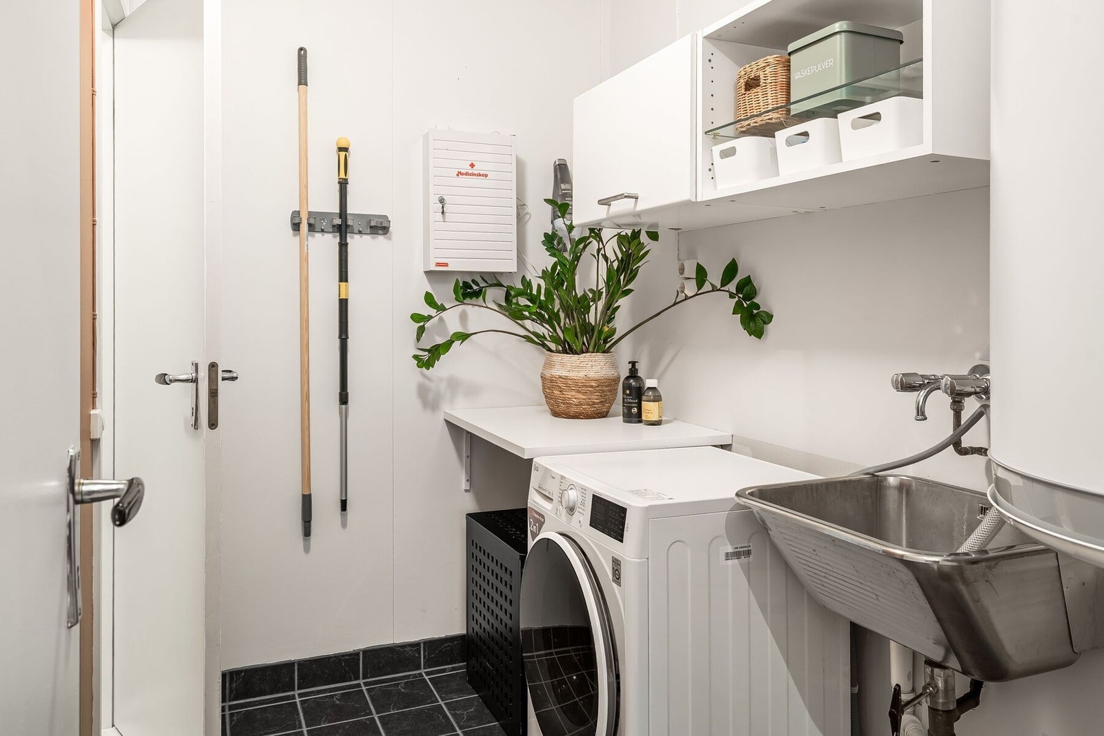 Vaskerom med skapplass, arbeidsbenk og en vask, med plass til både vaskemaskin og tørketrommel. Galleribilde