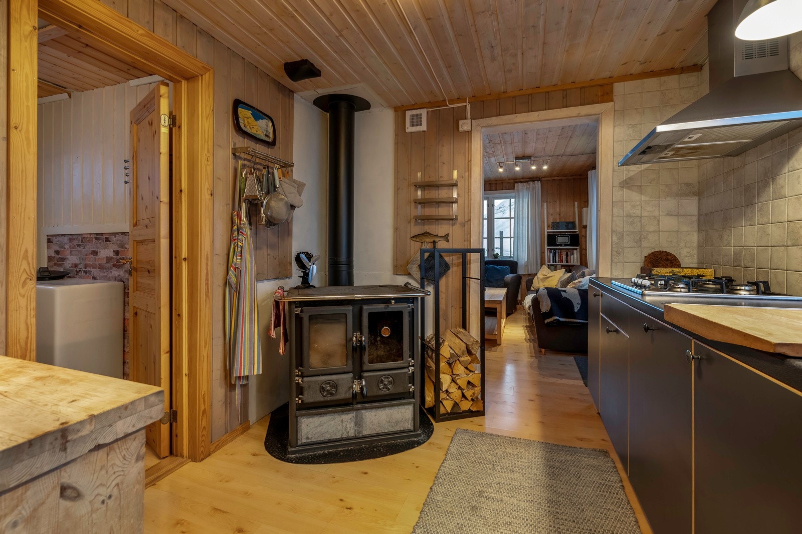 På kjøkkenet er det en koselig og effektiv vedovn. Her har eier montert innsugsvifte som trekker varmen fra peisen og fører den til inngangspartiet Galleribilde