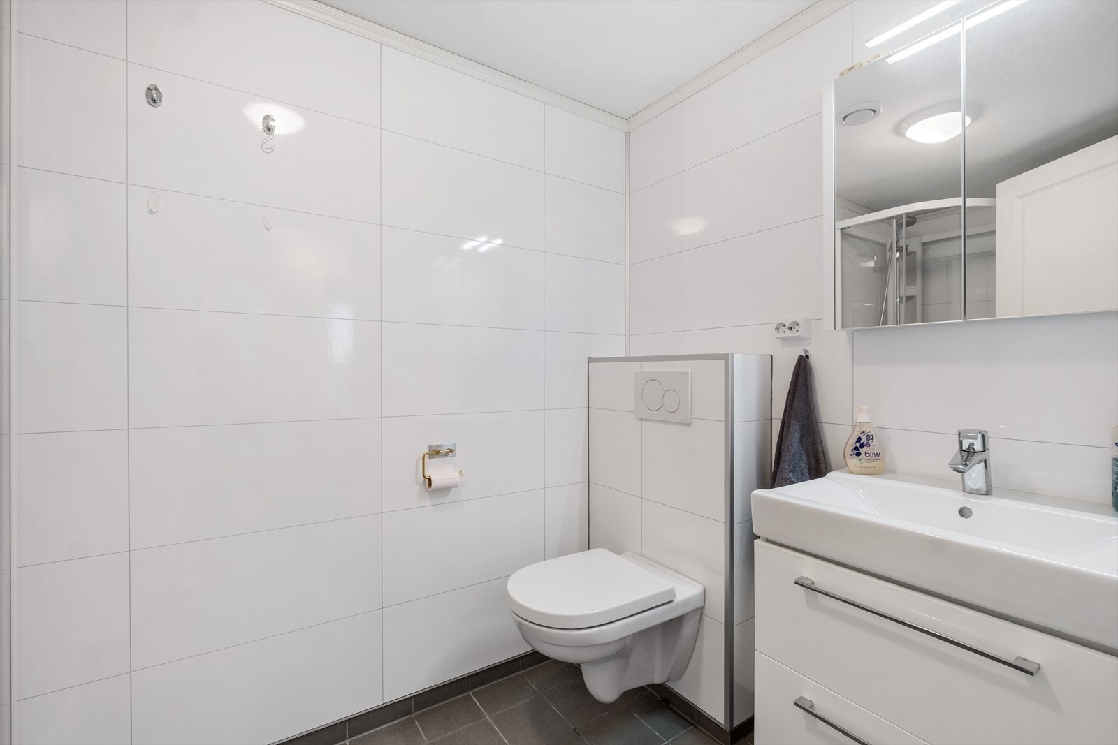 Badet er innredet med nedfelt servant, veggmontert toalett og dusjkabinett. Galleribilde