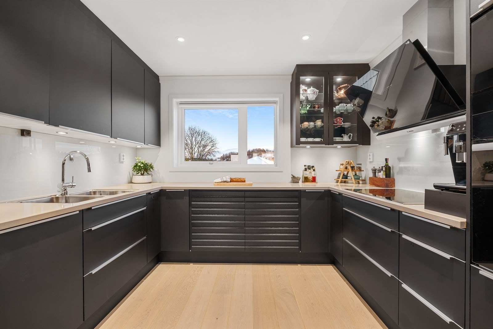 Stilrent kjøkken med sorte fronter og laminat benkeplate med underlimt vask. Galleribilde