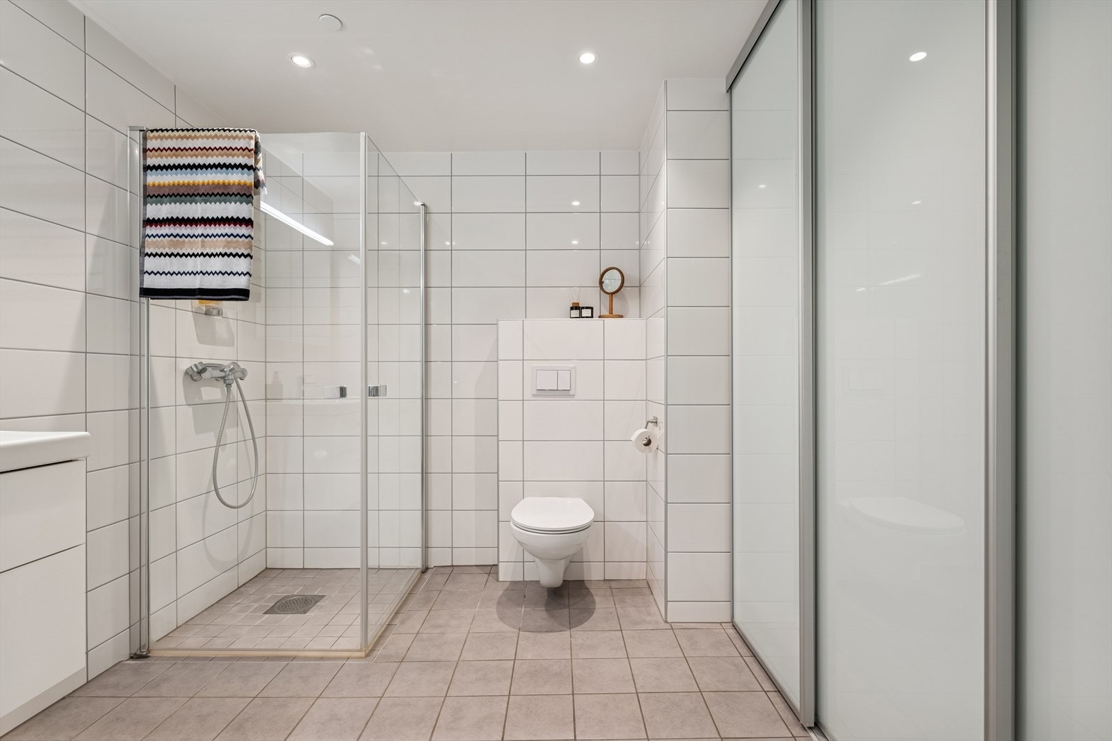 Praktisk skyvedørsløsning som skjuler vaskeromsdelen med smarte oppbevaringsmuligheter. Galleribilde