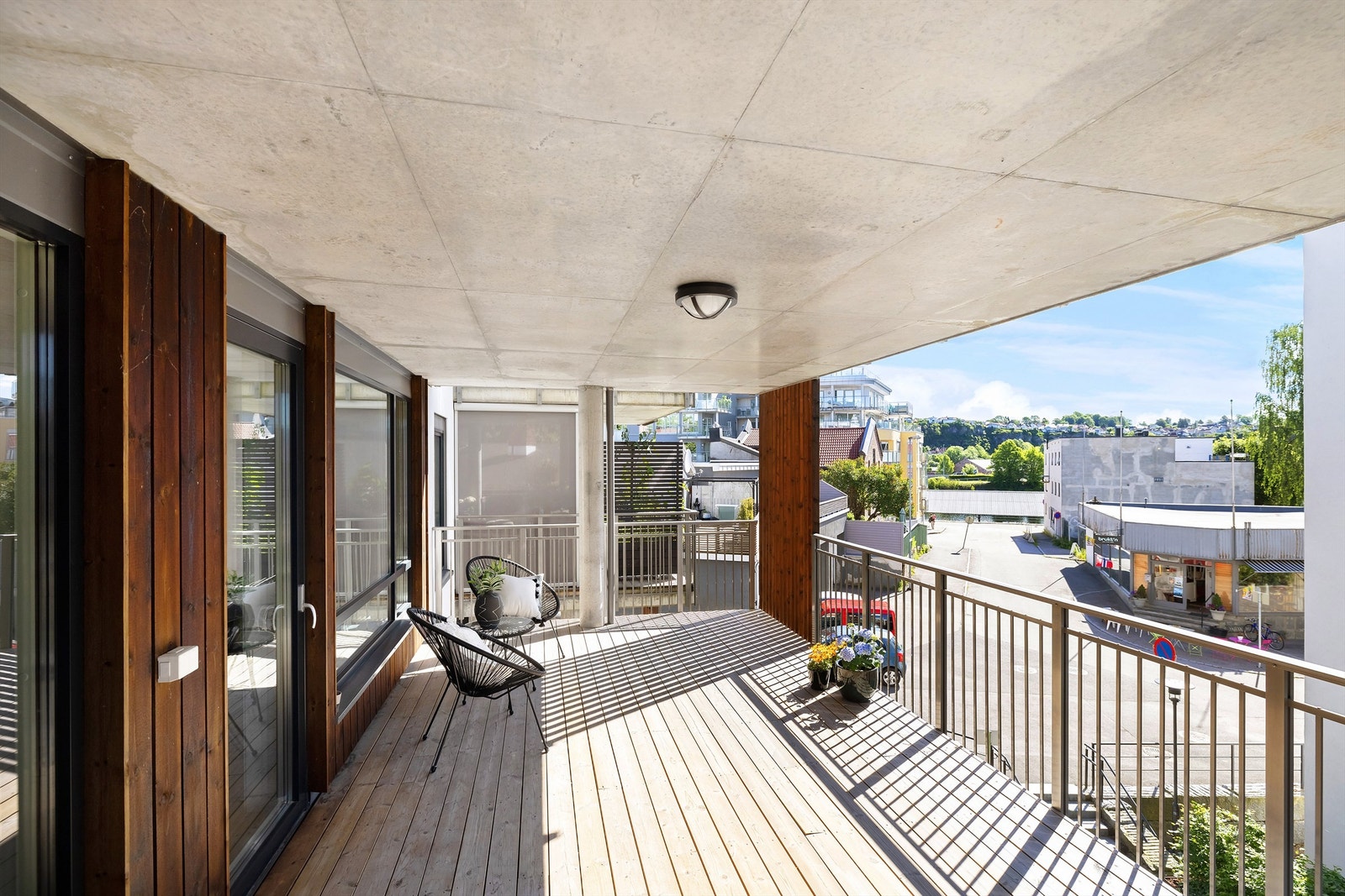 Balkong belagt med terrassebord og rekkverk av metall, samt noe treverk med stående spiler. Galleribilde