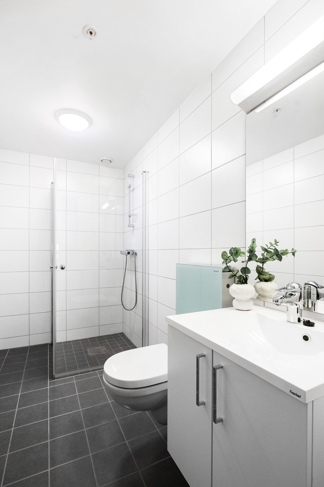 Bad 1. Flislagt bad med varmekabler. Innredning med slette fronter, heldekkende servant, speil, overlys og stikkontakt. Dusjhjørne. Galleribilde