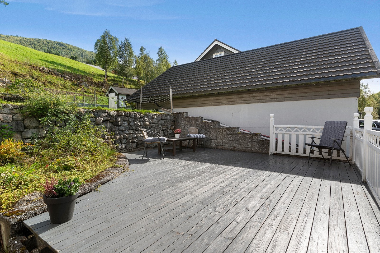 Her er det en steinmur som deler hagen på denne siden i to nivå. Galleribilde