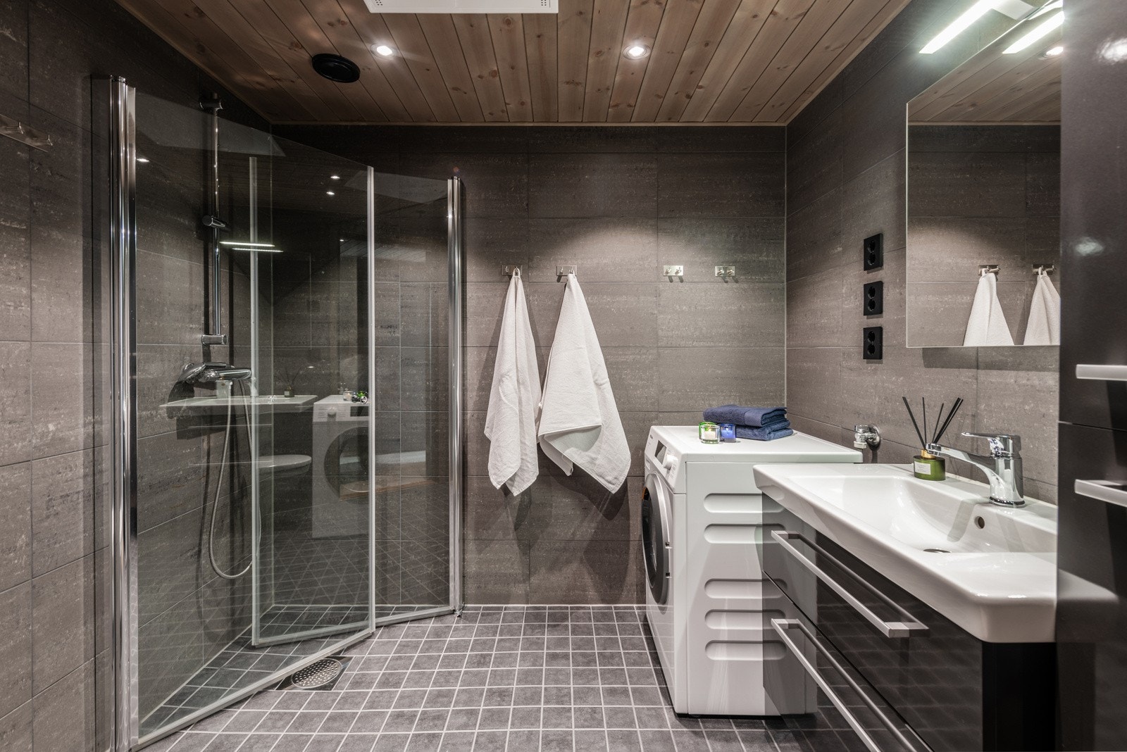 Delikat bad med grå flser og panel i taket. Galleribilde