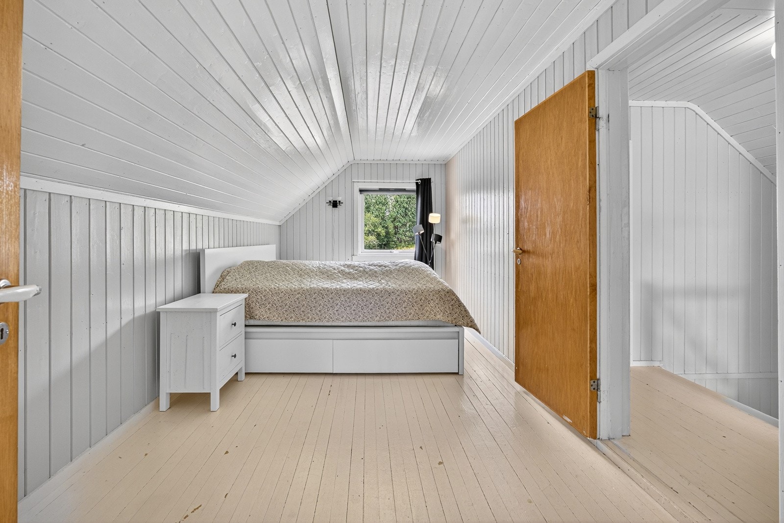 Boligens hovedsoverom er av generøs størrelse med god plass til dobbeltseng med tilhørende nattbord. Rommet har malt panel på veggflater, sjarmerende skråtak og malte heltre gulvbord. Galleribilde