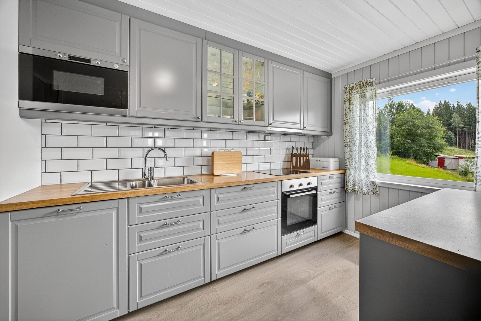 Det er nedfelt oppvaskkum med ett-greps armatur, benkebelysning og stikkontakter over benk, samt fliser mellom benkeplate og overskap. Galleribilde