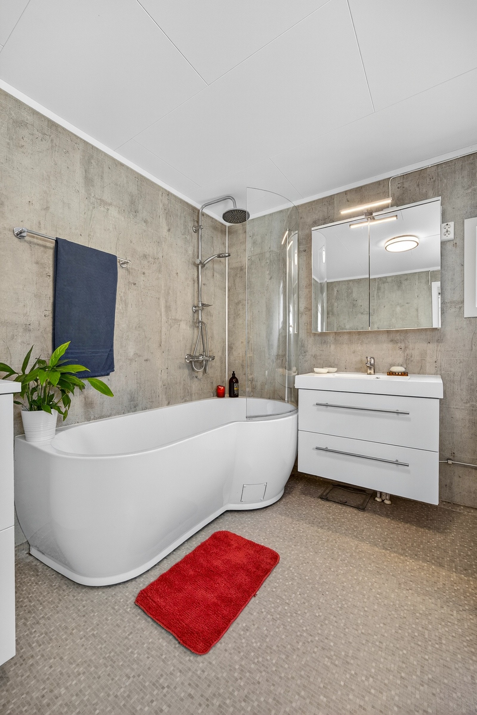 Rommet er innredet med moderne servantmøblement, tilhørende speilskap, toalett, samt badekar med glassvegg og regnfallsdusj. Galleribilde