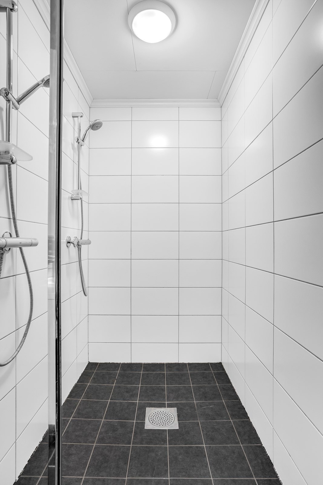 Romslig dusjnisje med glassdør og to dusjhoder. Galleribilde