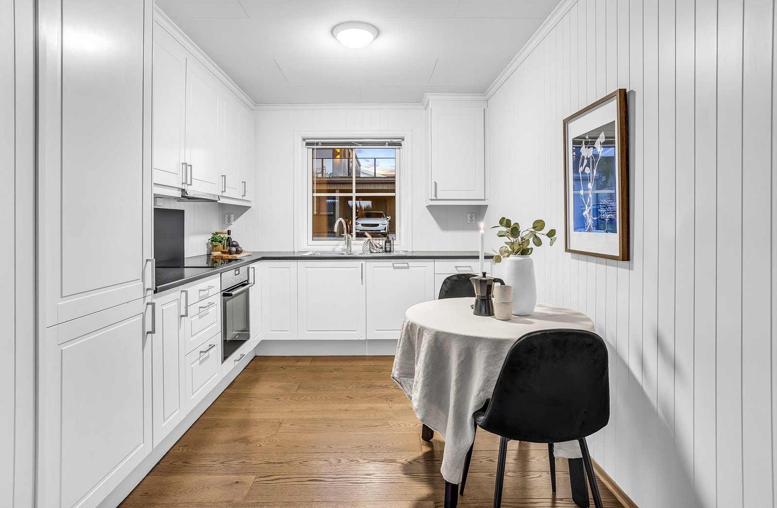 Kjøkkenet har en pen innredning med profilerte, hvite fronter og laminatbenkeplate. Galleribilde