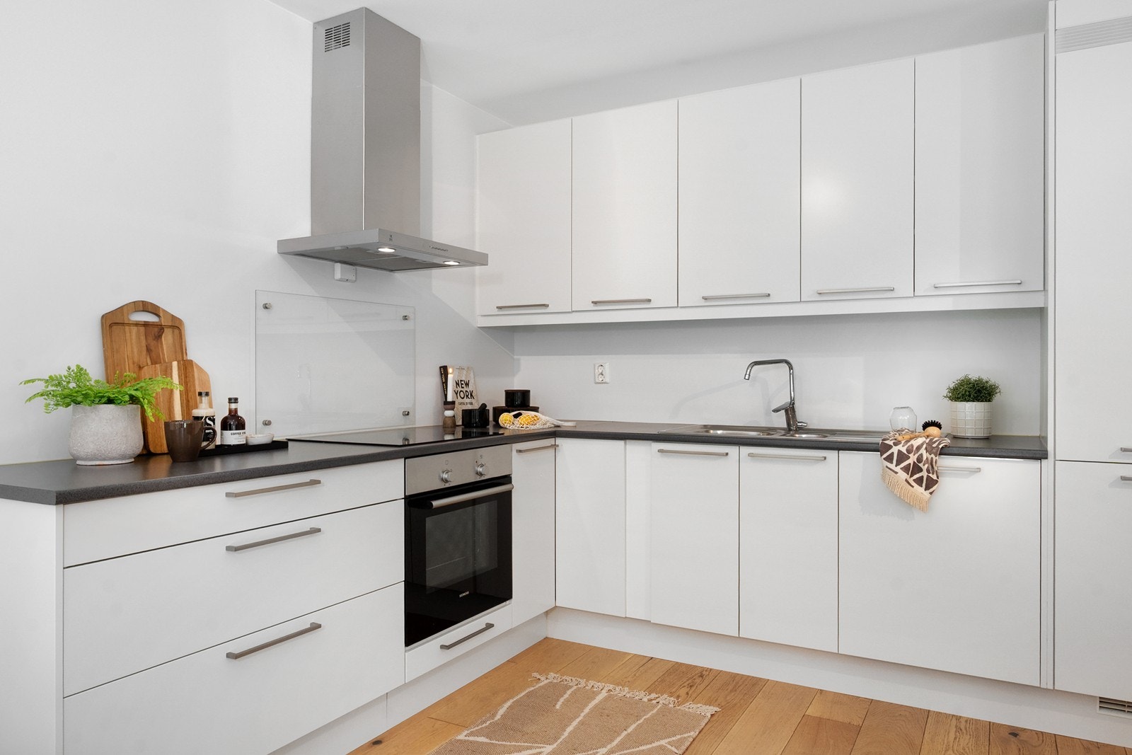 Kjøkkenet er i åpen løsning mot stuen og er levert av Sigdal. Innredningen har hvite fronter og laminat benkeplate med planlimt kum i rustfritt stål. Galleribilde