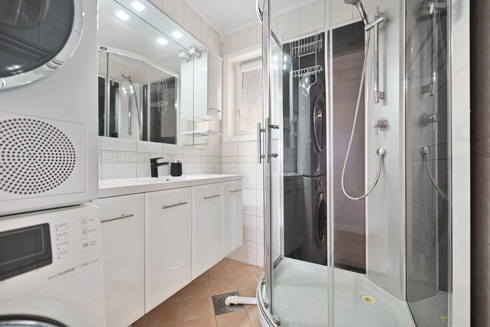 Badet har innredning med nedfelt servant, dusjkabinett og opplegg for vaskemaskin og tørketrommel. Galleribilde