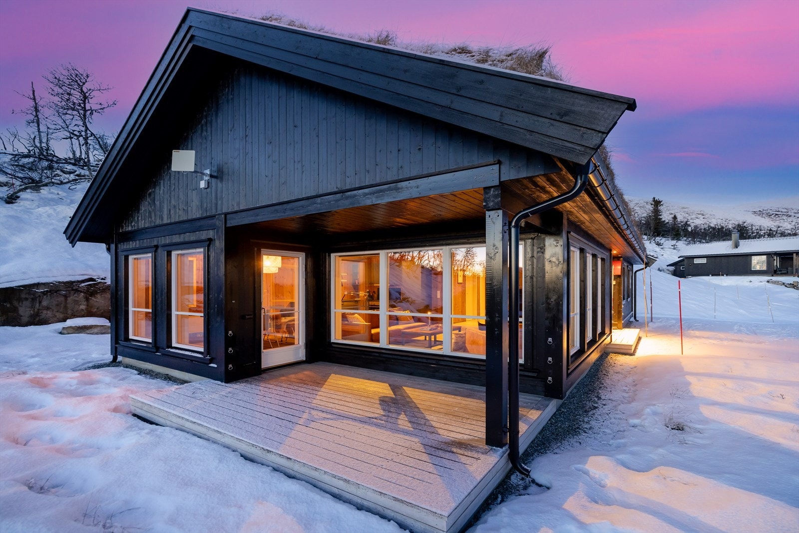 Hytten er pent mørk beiset og torvtak. Galleribilde