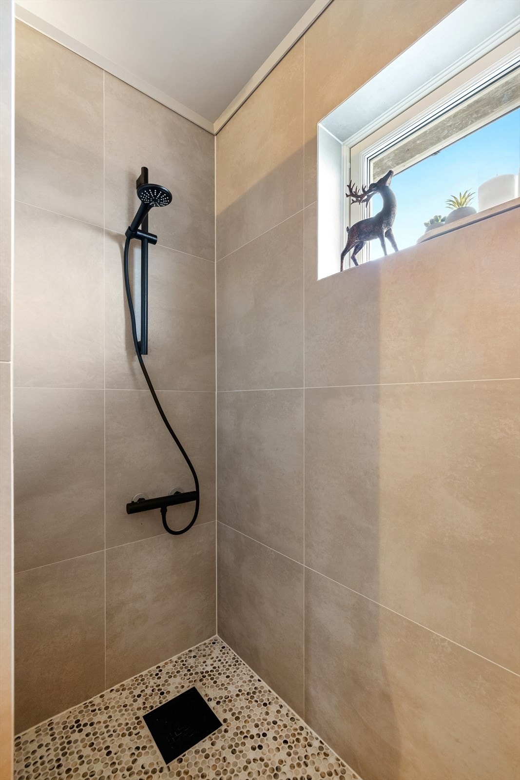 Videre er det en stor dusjnisje med mosaikkfliser på gulvet og 60 x 60 fliser på veggene. Galleribilde