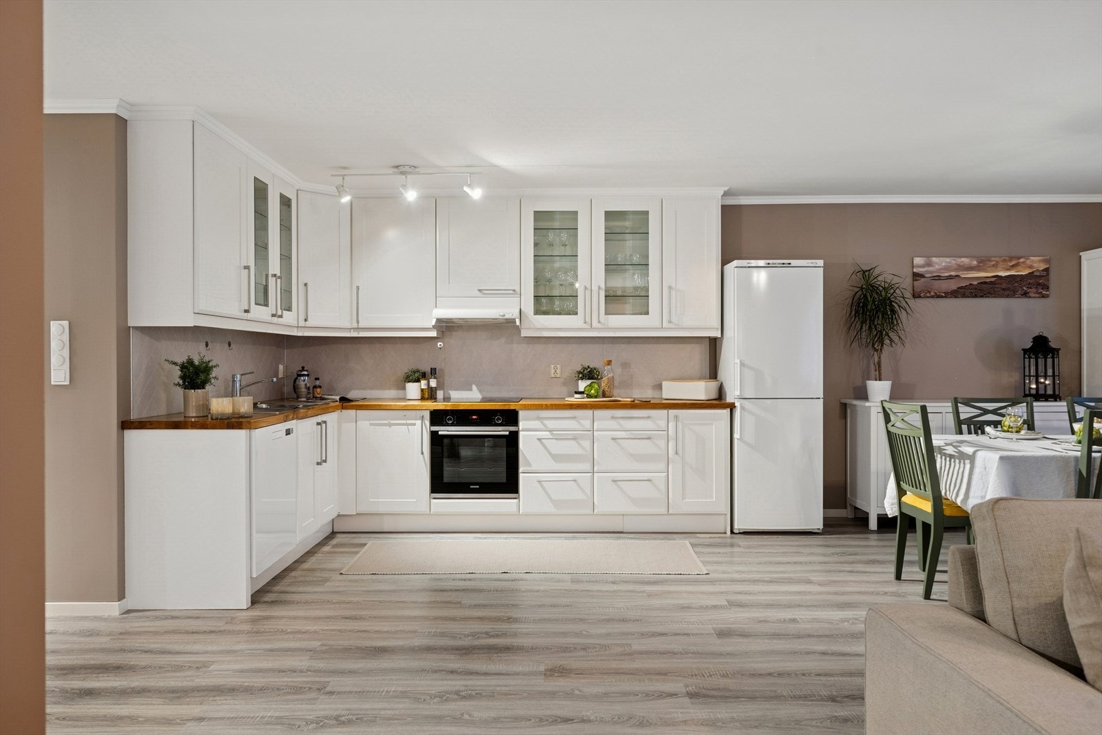 Kjøkkenet har en klassisk og tidløs stil med hvite fronter og elegante glassdører på overskapene som gir et luftig og stilrent uttrykk. Galleribilde