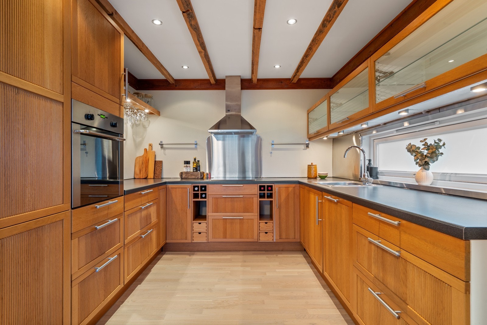Kjøkken med solide innredningsløsninger, synlige takbjelker og varme treflater - en kombinasjon av tradisjon og moderne funksjonalitet. Galleribilde