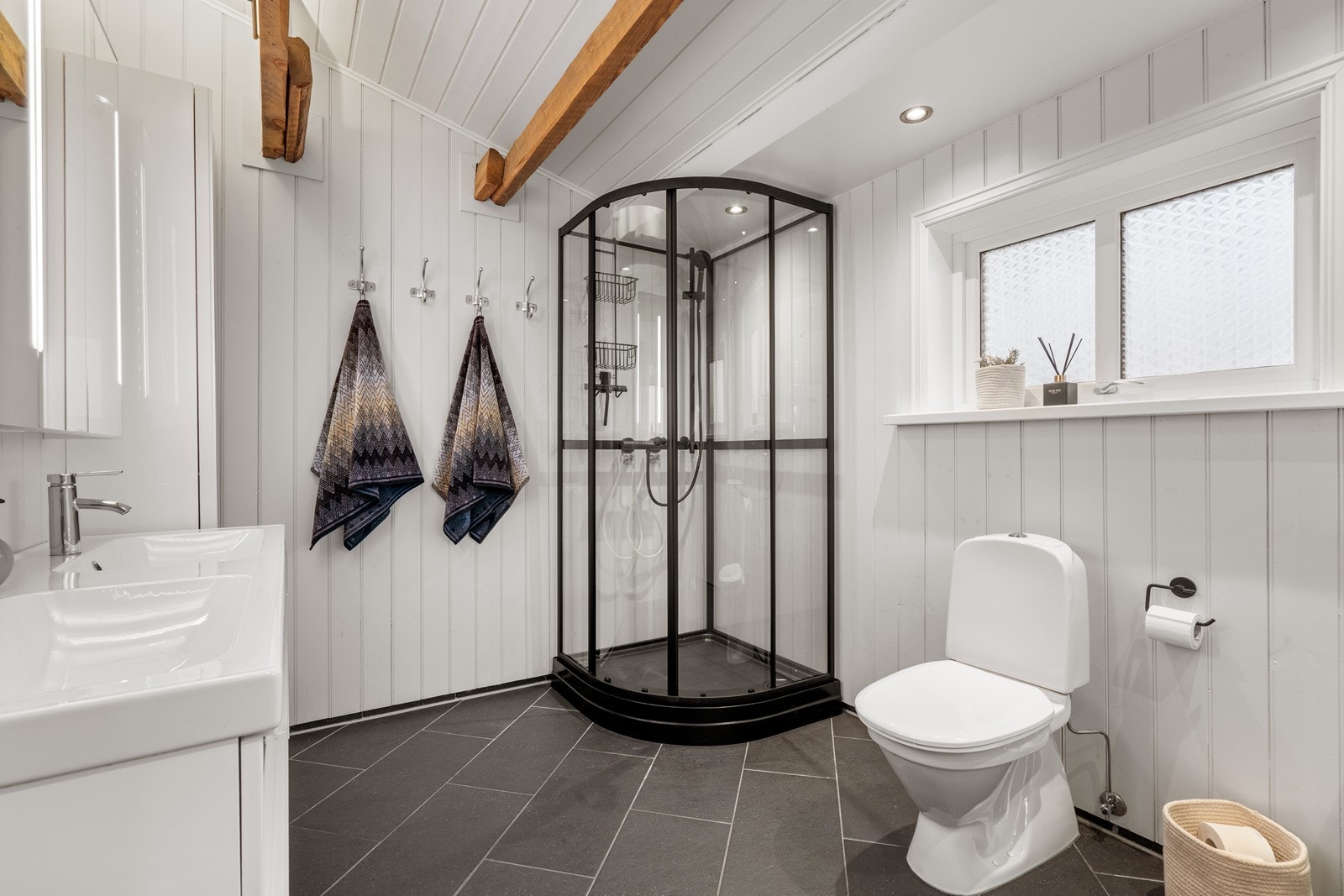 Lyst bad av god størrelse og flislagt gulv. Herlige detaljer med synlige takbjelker som gir rommet en varm og lun atmosfære. Galleribilde