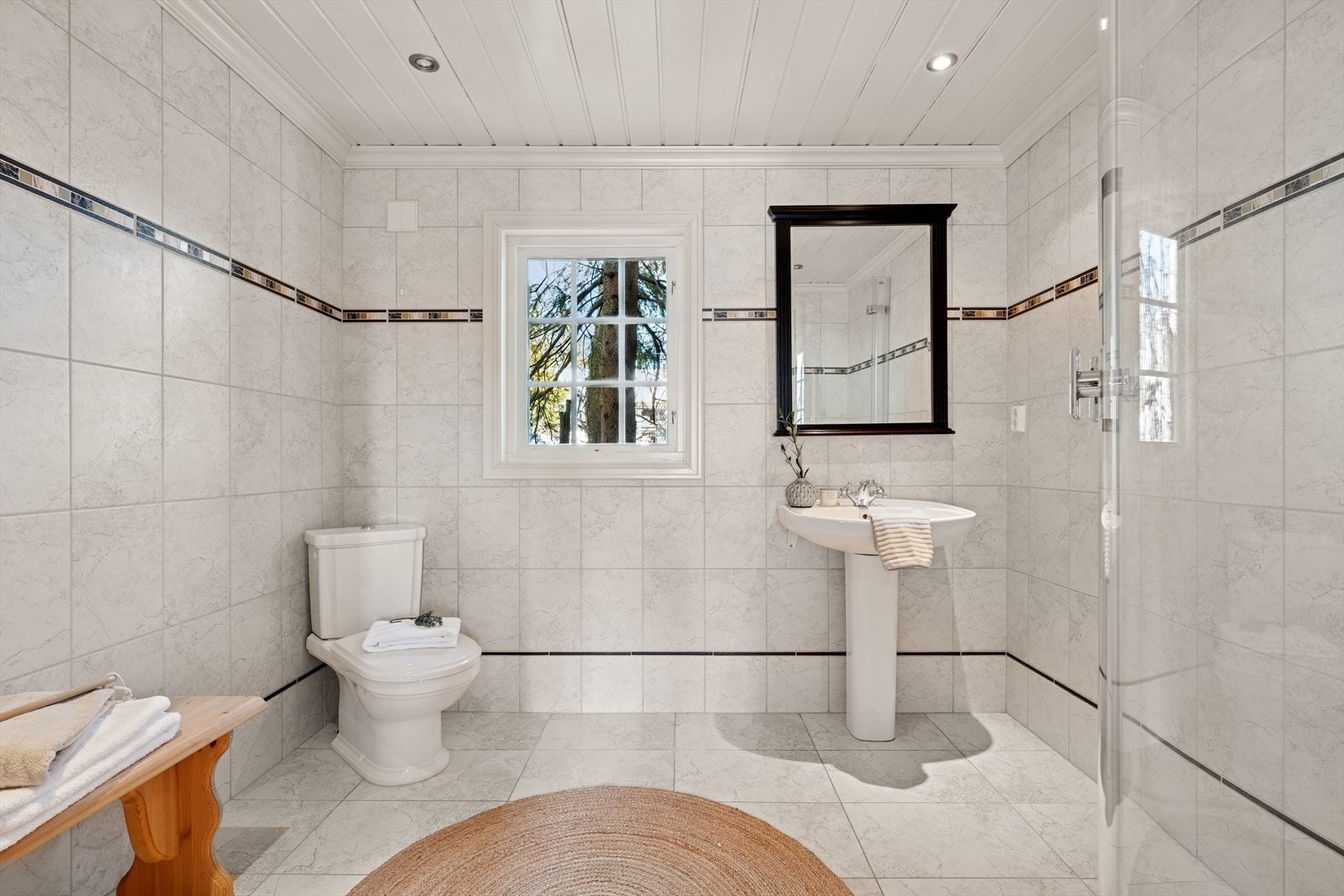 Dette badet er innredet med servant med søyle, gulvmontert toalett og dusjhjørne med dusjkar. Galleribilde