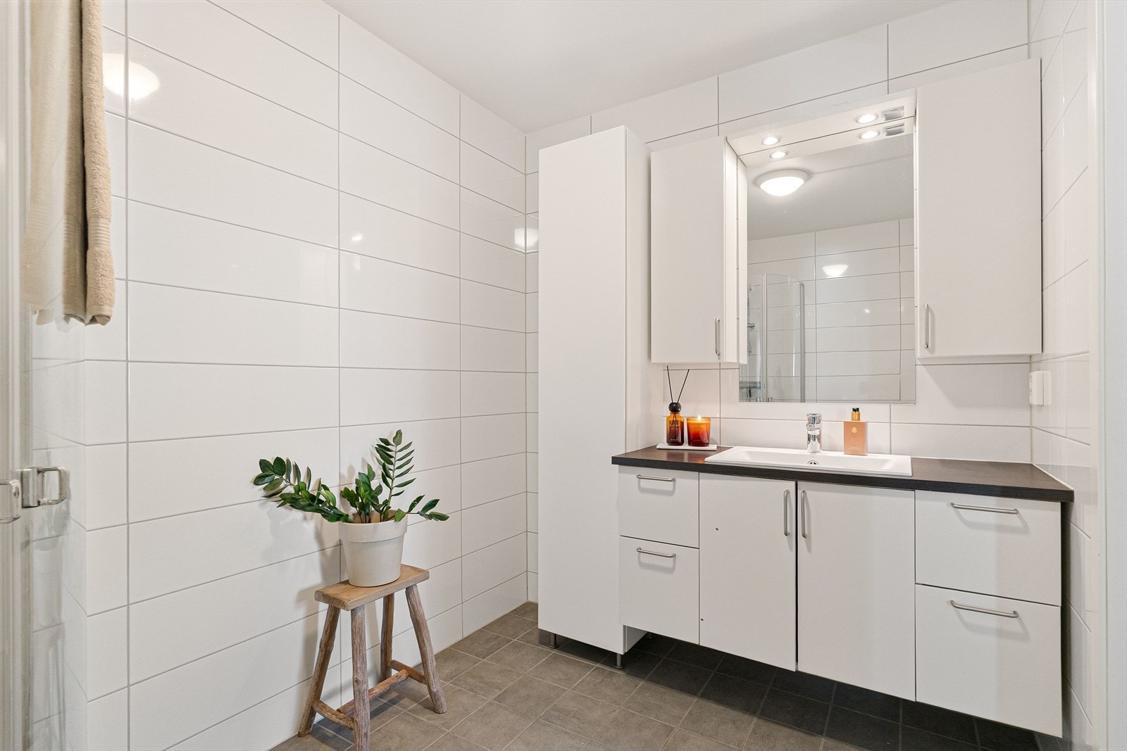 Innredningen består av servant nedfelt i mørk benkeplate, hvitt servantskap, matchende veggskap og speil med belysning. Galleribilde