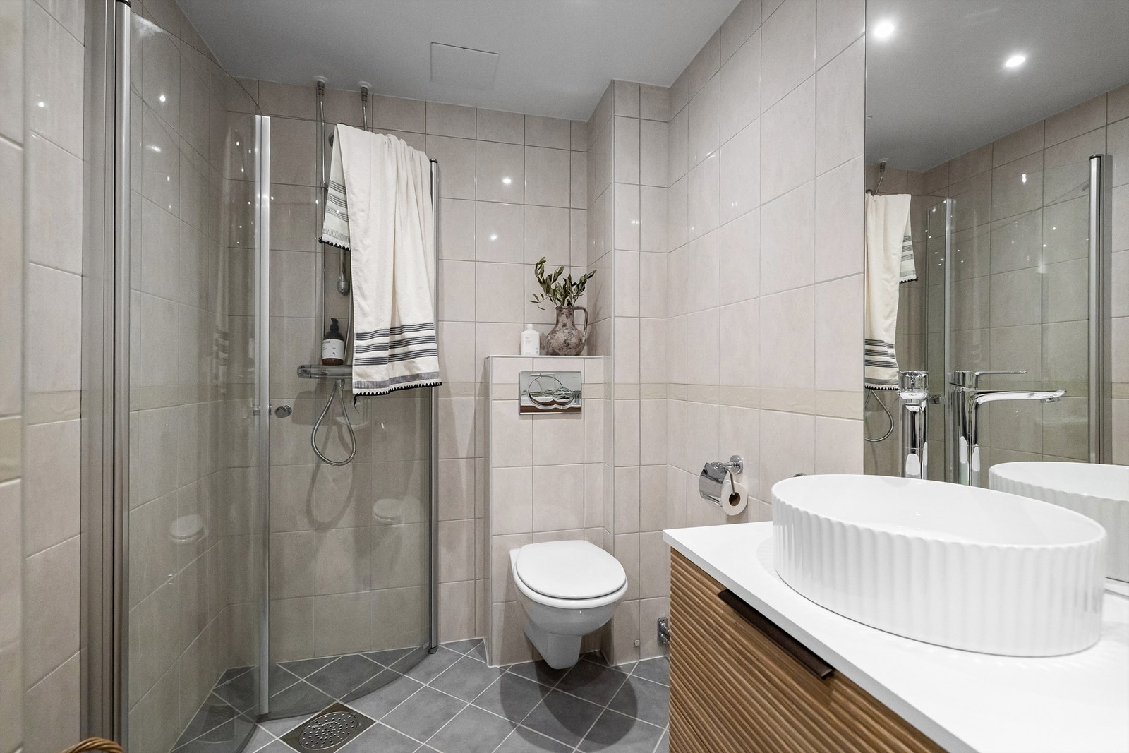 Badet er videre utstyrt med vegghengt toalett, dusjhjørne med innfellbare glassdører og opplegg til vaskemaskin Galleribilde