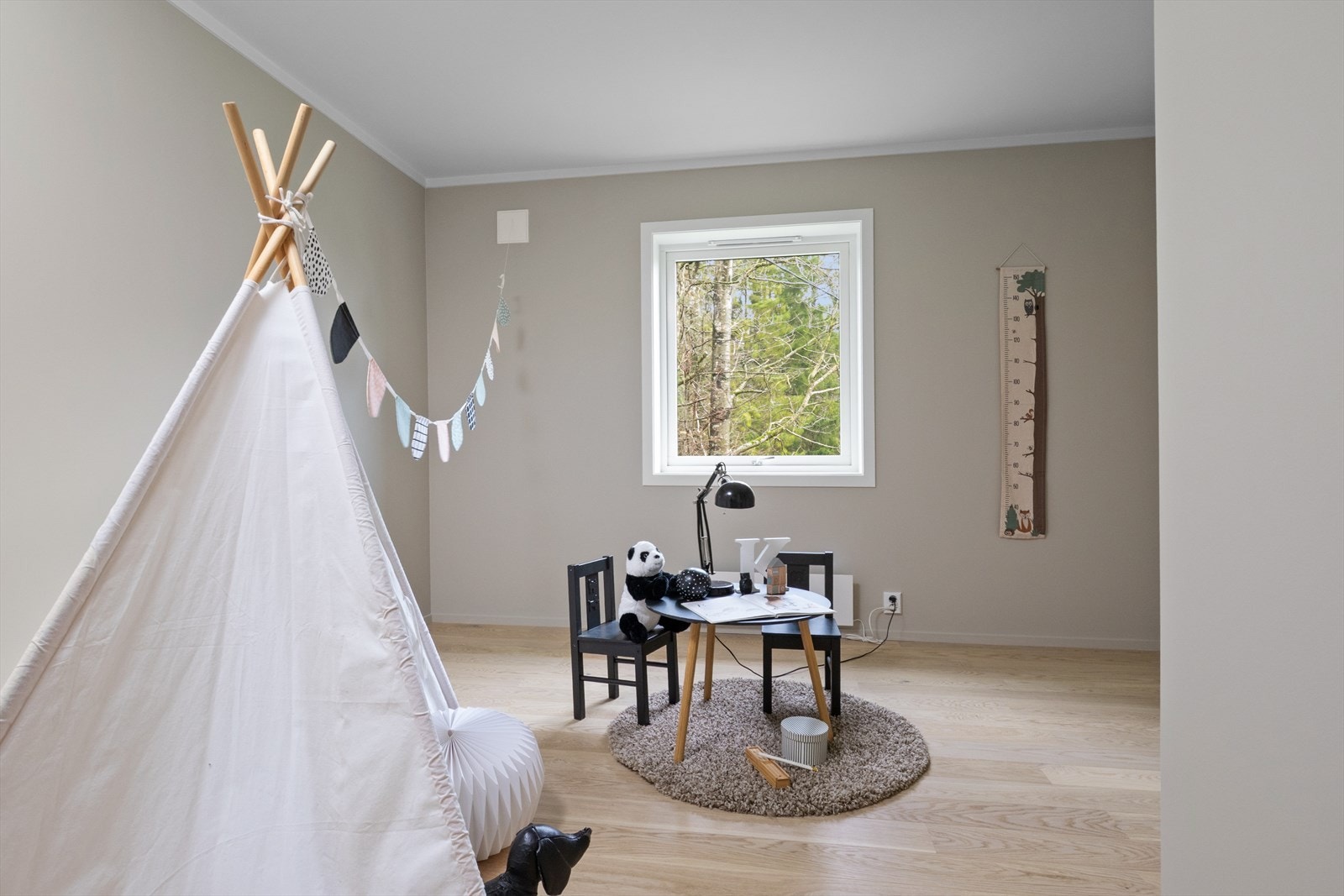 Lyst barnerom med parkettgulv og vindu som gir naturlig lys. Galleribilde