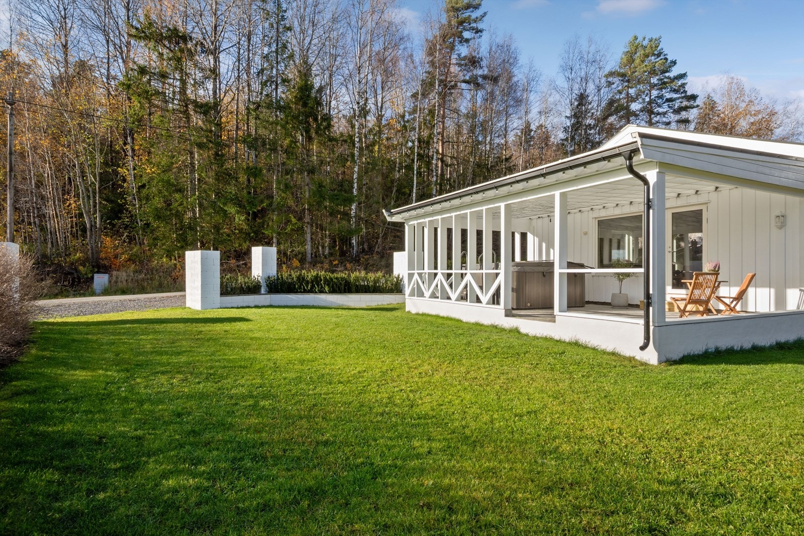 Den overbygde terrassen er plassert i en velstelt hage med gressplen. Galleribilde