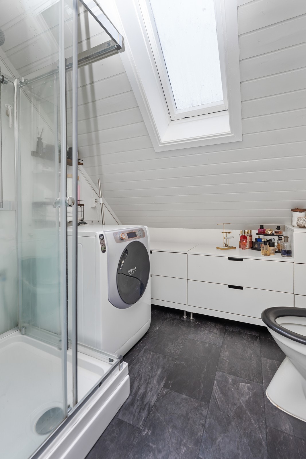 Badet har belegg på gulv, dusjkabinett opplegg til vaskemaskin, toalett og innredning med nedfelt servant. Galleribilde