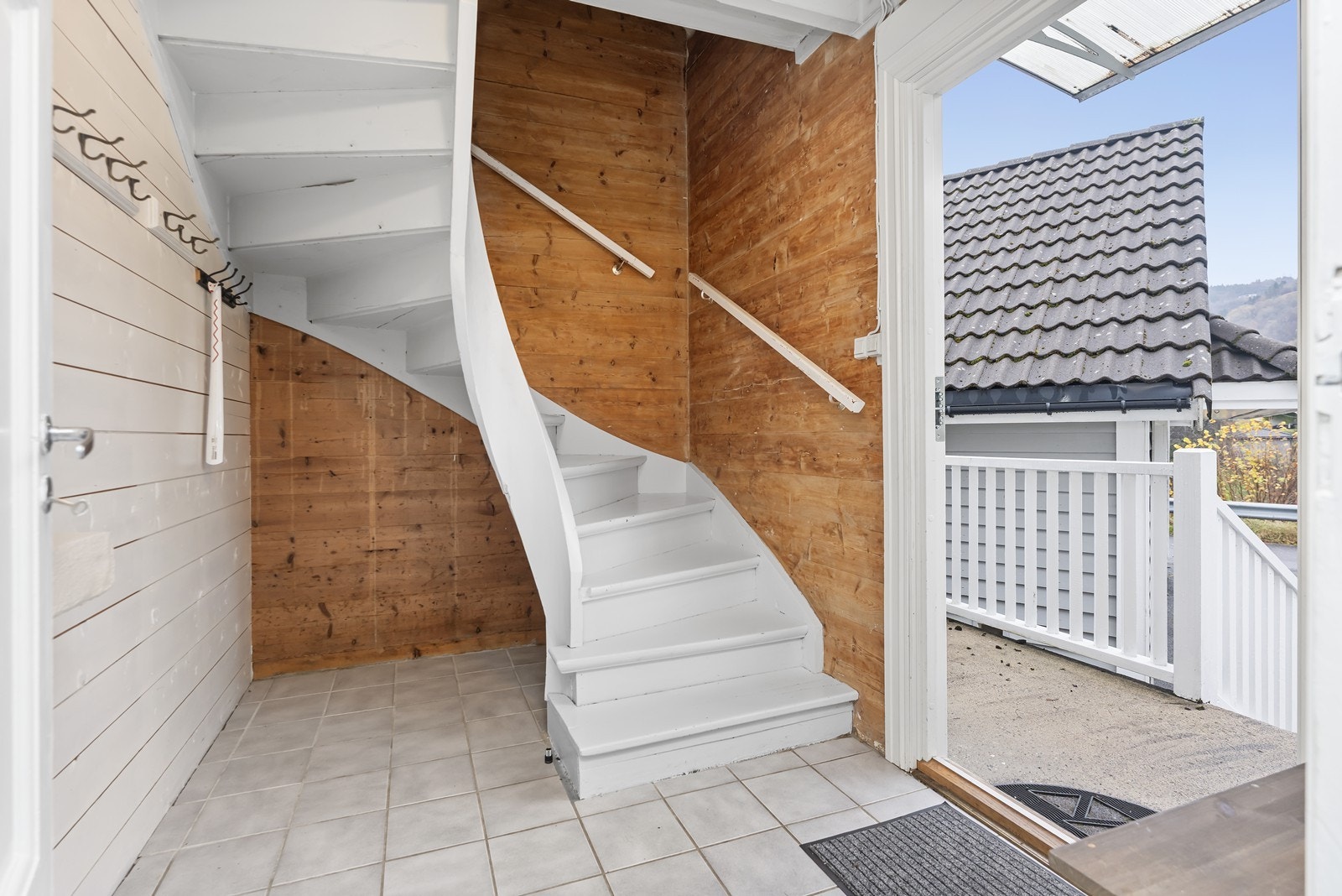 Inngangsparti hvor det også er trapp opp til andre etasje. Rommet har flislagt gulv og opp trappen er det beholdt de laftede tømmerveggene som gir et varmt og rustikt uttrykk. Galleribilde