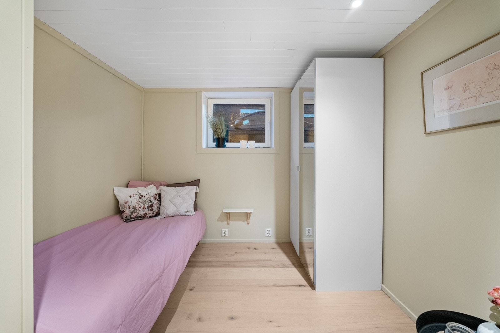 Lyst soverom med plass til seng og skap, og vindu som gir naturlig lysinnslipp. Galleribilde