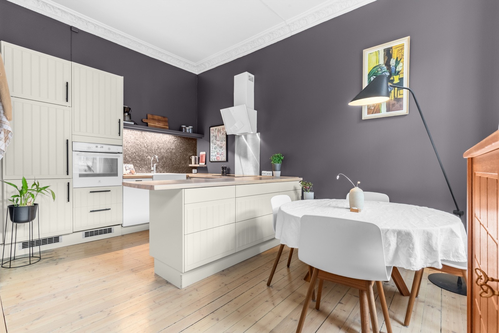 Kjøkkenet fremstår som innbydende med lyse, profilerte fronter og svarte stålgrep Galleribilde