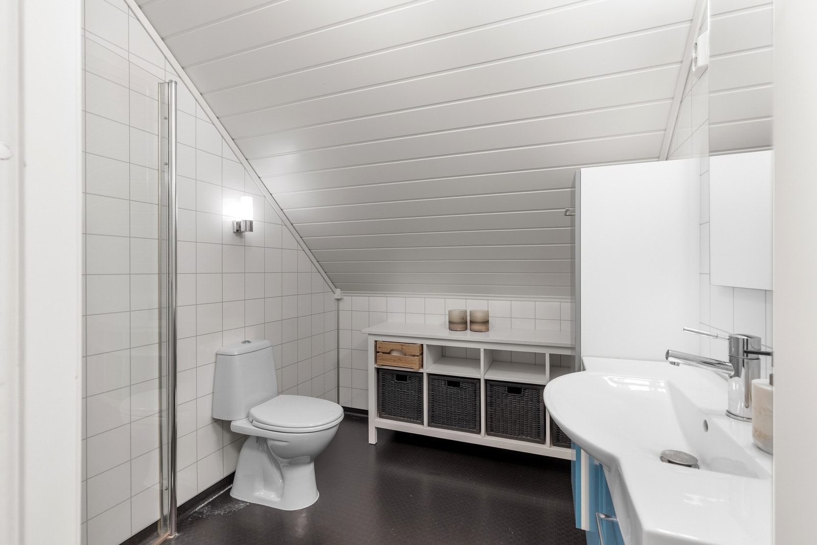 Badet er utstyrt med dusjhjørne med innfellbare dusjdører, wc, servantskap og mekanisk avtrekk. Galleribilde