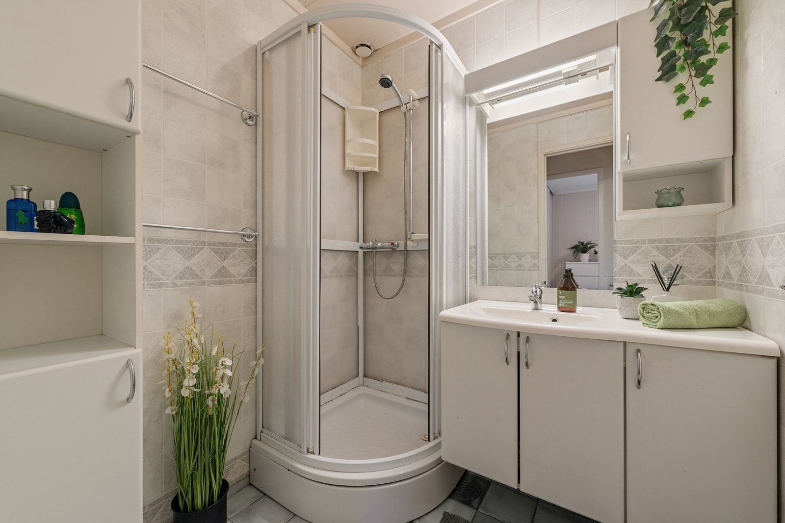 Et lyst og delikat baderom med dusjkabinett og servant med god oppbevaringsplass. Galleribilde