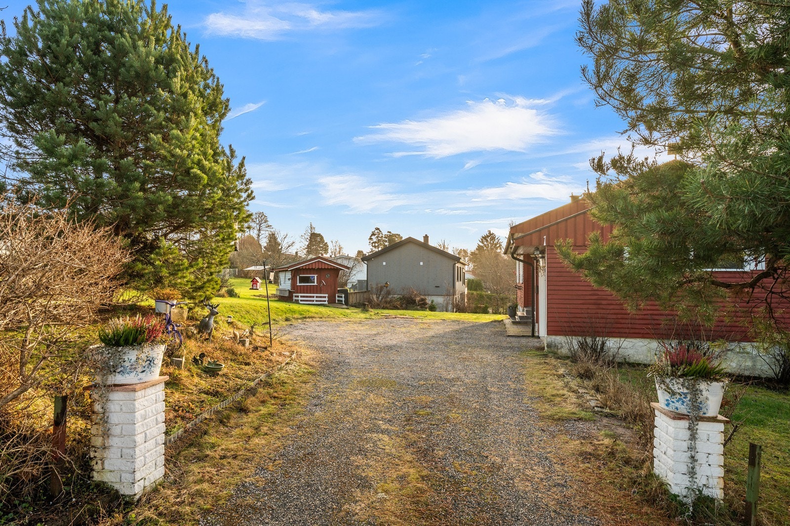 Gruset innkjørsel og gårdsplass med god plass til parkering av flere biler. Galleribilde