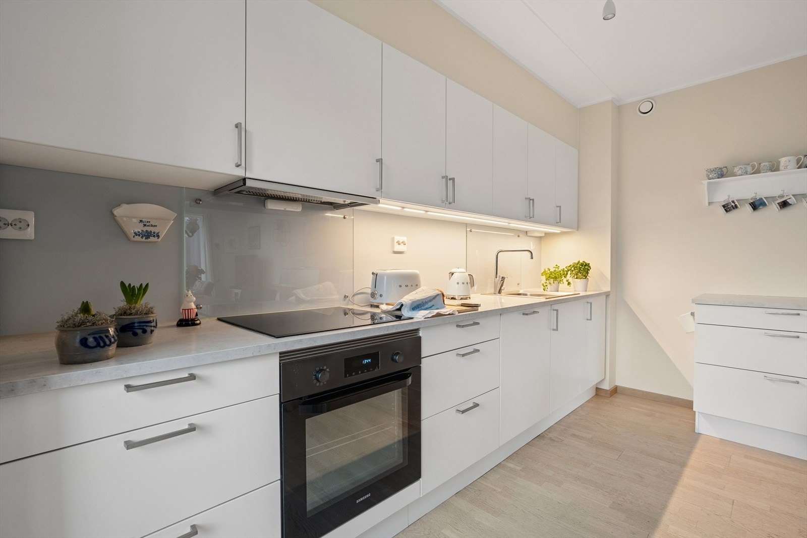 Pent kjøkken med integrerte hvitevarer som komfyr, platetopp, kjøleskap og oppvaskmaskin. Galleribilde