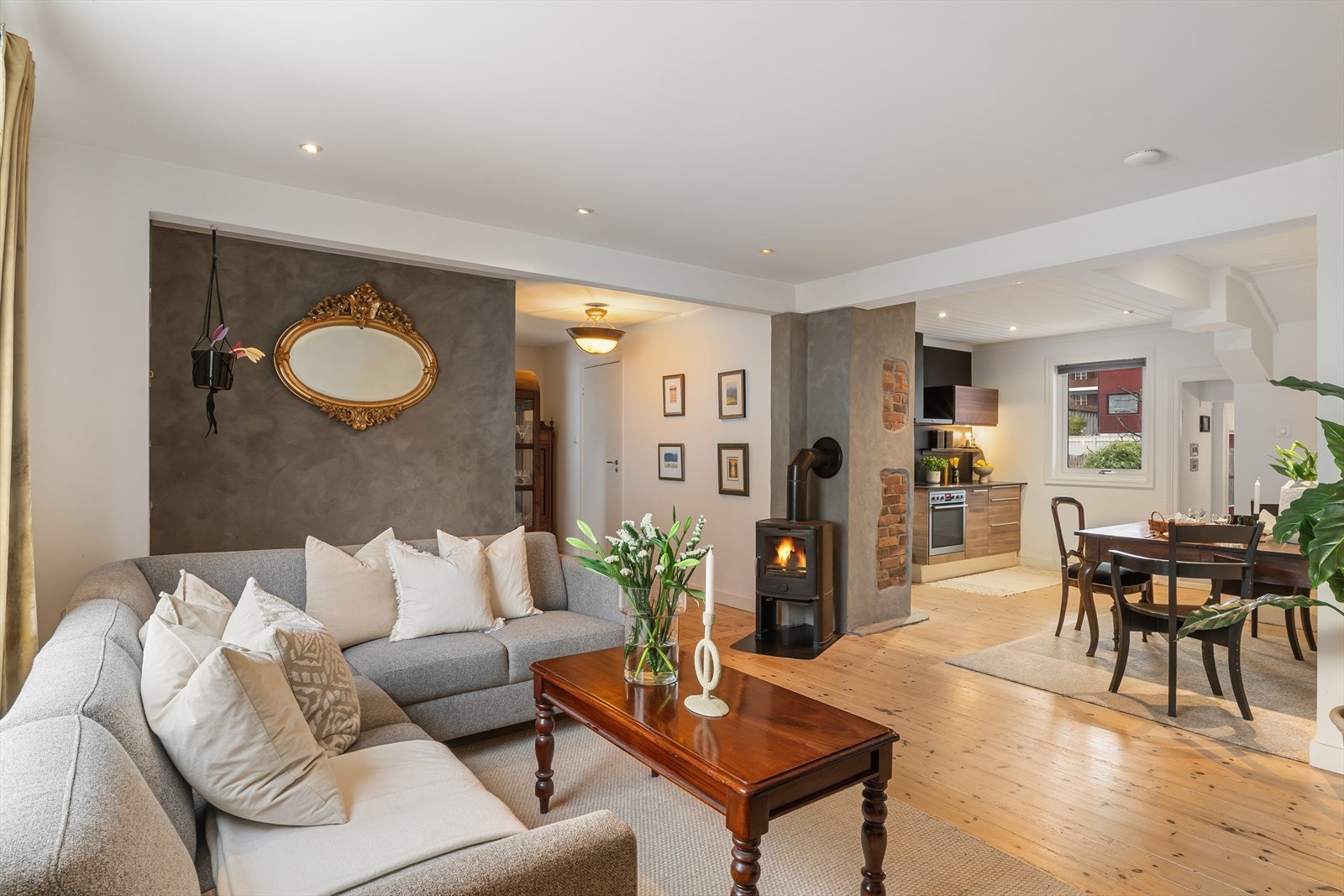 Stue, kjøkken og spiseplass i åpen løsning med vedovn. Downlights i tak. Galleribilde