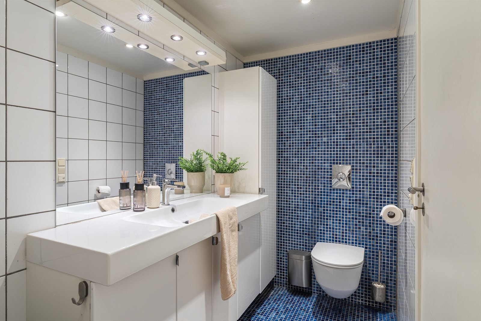 Helfliset bad med vegghengt wc, badekar med dusj, vask i møbel og opplegg for vaskemaskin og tørketrommel. Galleribilde