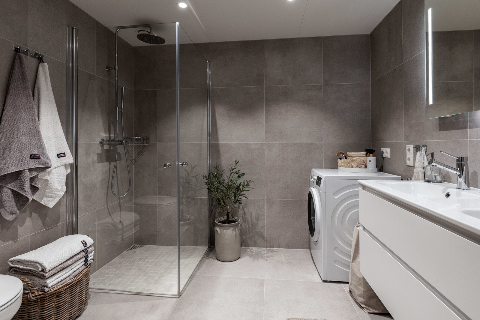 Badet har store gulv- og veggfliser, varmekabler og downlights. Dusjhjørnet har mosaikkfliser, samt regnfall og innfellbare dører i glass. Galleribilde