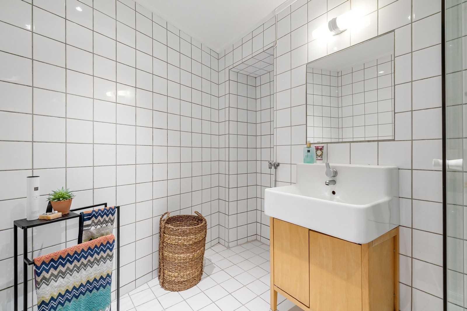 Flislagt bad med varmekabler i gulv, innredet med servantseksjon med skap, speil og dusjkabinett. Galleribilde