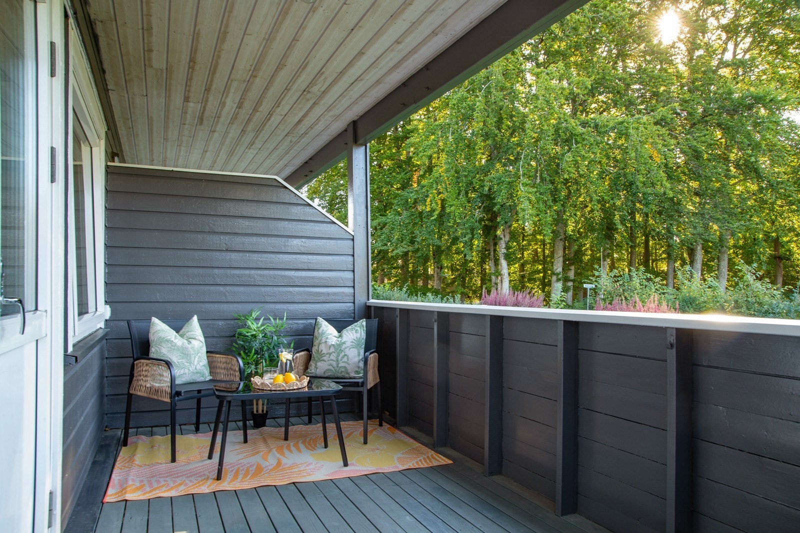 Den overbygde verandaen på 9 kvm byr på utsyn mot Bøkeskogen i øst og felles hage. Verandaen ble malt og gulvet beiset i 2025. Galleribilde