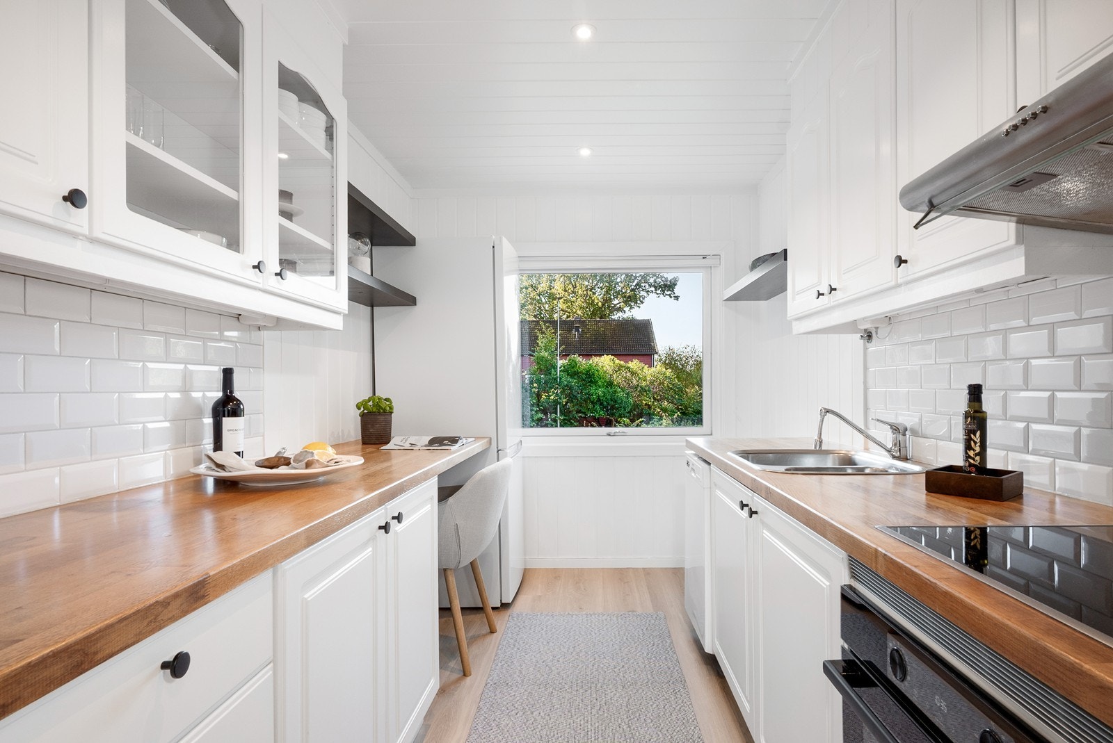 Innredningen har hvite fronter, heltre benkeplate og en liten spiseplass ved vinduet. Over benken er det delikate fliser. Galleribilde