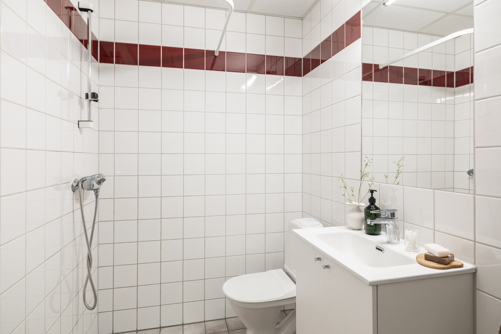 Baderommet er utstyrt med lyst servantskap med speil og belysning over, dusjhjørne med forheng og gulvstående toalett. Galleribilde